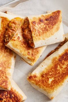 three quesadillas cut in half sitting on top of a piece of wax paper