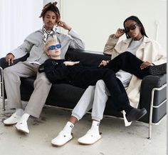 three people sitting on a couch with one person wearing sunglasses and the other in a suit