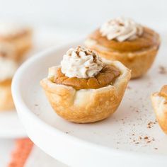 mini pies with whipped cream on top sit on a white plate