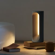 a table with a lamp and some books on top of it next to a cup