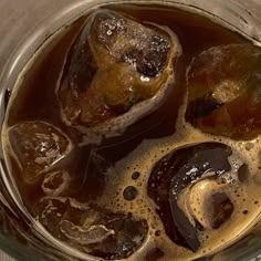 some ice cubes are sitting in a glass with brown liquid on the top and bottom