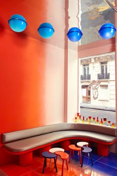 an orange and blue room with benches, stools and tables in front of a window