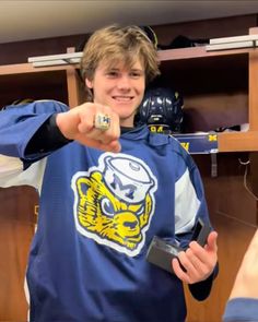 a young man in a hockey jersey pointing at the camera