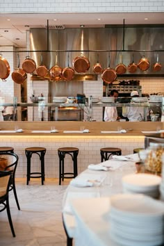 a restaurant kitchen filled with lots of pots and pans hanging from the ceiling over tables