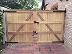 a wooden gate is open on a brick walkway