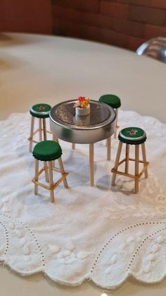 a miniature table and stools on a white doily