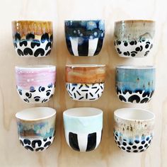 there are many bowls on the wall with different designs and colors in them, all hand painted