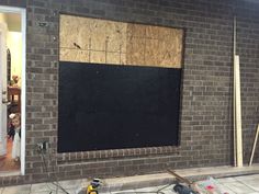 a blackboard is being installed on the side of a brick wall in front of a doorway