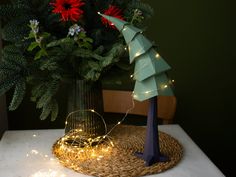 a small christmas tree on a table next to a vase with flowers