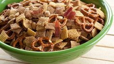 a green bowl filled with cereal and pretzels on top of a wooden table