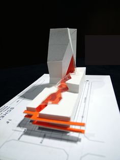 an architectural model is shown on top of blueprints and orange lines are drawn across the paper