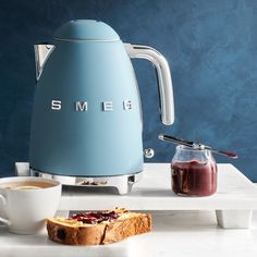 a toaster sitting on top of a white counter next to a cup of coffee