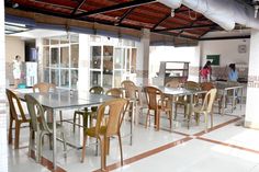 an indoor dining area with tables and chairs in the center, people are standing around