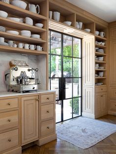 a kitchen with wooden cabinets and white dishes on the shelves