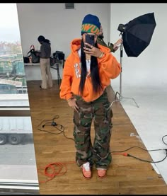 camo pants cargo pants outfit orange jacket outfit beanie grean and orange Foam Posites Outfits, Color Cordinate Outfit Friend Group, Hollywood Shack Outfits, Cargo Hoodie Outfit, Drip Outfit Women, Lucki Concert Fit, Baggy Outfits Black Women, Oversized Cargo Pants Outfit, Cute Winter Birthday Outfits