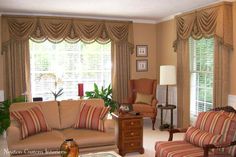 a living room filled with furniture and flowers on the table in front of two windows