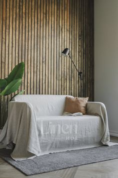 a white couch sitting on top of a hard wood floor next to a green plant