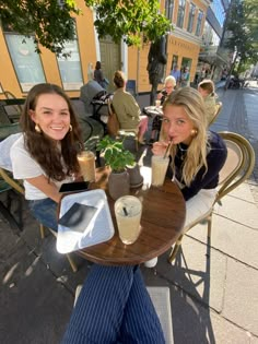 two women sitting at an outdoor table with drinks