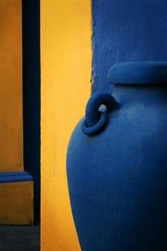 a large blue vase sitting next to a yellow wall