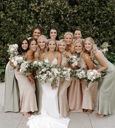 a group of women standing next to each other wearing dresses and holding bouquets in their hands