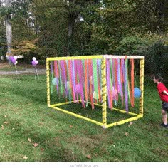 a little boy standing in front of a colorful box with balloons on it and streamers