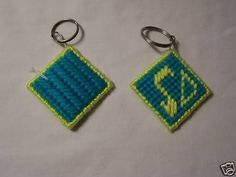 two blue and green keychains are sitting on a white tablecloth, one has a small diamond in the middle