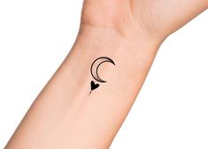 a small tattoo on the wrist of a person with a crescent moon and heart in black ink