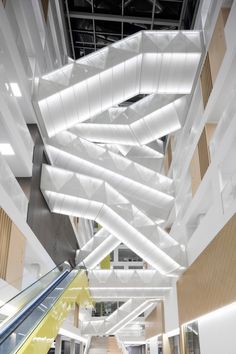 an escalator in a large building with lots of white beams hanging from the ceiling