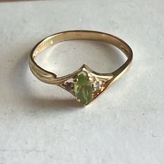 a yellow gold ring with an oval shaped peridolite and two small white diamonds