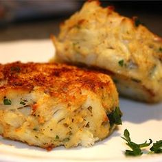 two crab cakes on a white plate with parsley sprig garnish