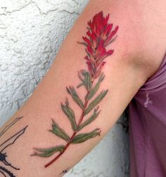 a woman with a tattoo on her arm has a red and green flower in it