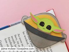 an origami star wars yoda in a hat on top of a book