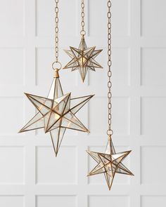 three gold stars hanging from chains against a white wall