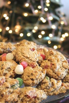 a plate full of cookies with m & m's on it and a christmas tree in the background