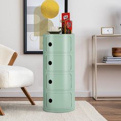 a green cabinet with four drawers in a living room next to a chair and table