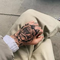 a woman's hand with a rose tattoo on it, sitting on the ground