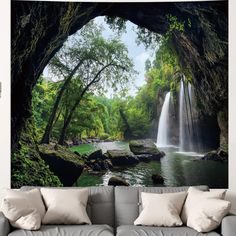 a living room with a couch and large wall mural depicting a waterfall in the forest