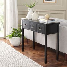 a black and white table with two vases sitting on it's side next to a couch