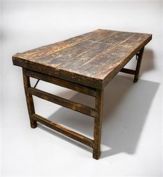 an old wooden table sitting on top of a white floor with no one around it