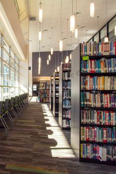 rows of chairs and tables in a library with lots of books on the shelves behind them