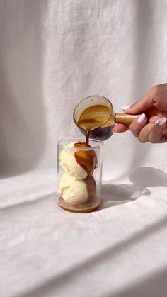 someone is pouring something into a glass with ice cream and caramel on the side