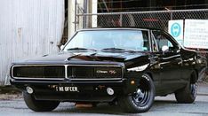 a black muscle car parked in front of a building