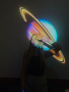 a woman is standing in front of a wall with an image of saturn on it