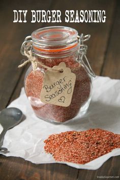 a jar filled with spices sitting on top of a wooden table next to a spoon