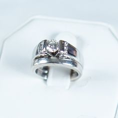 a couple of rings sitting on top of a white box with a diamond in the middle