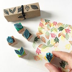 someone is stamping leaves on a piece of paper next to some rubber stamps and a box