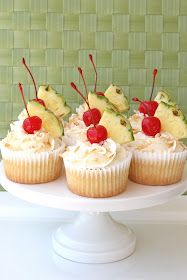 cupcakes topped with pineapple slices and cherries on a white cake plate