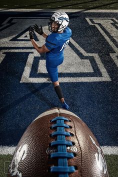 a football player in blue and white is about to kick the ball on the field