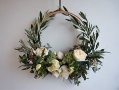 a wreath hanging on the wall with flowers and greenery