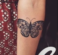 a woman's arm with a black and white butterfly tattoo on the left forearm